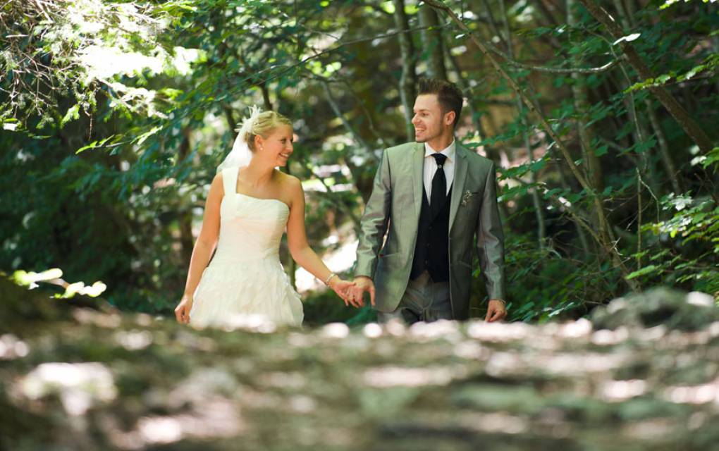 Hochzeitspaar läuft einen Waldweg entlang