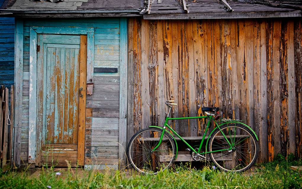 Grünes Fahrrad vor Holzschuppen