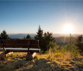 Wanderer machen eine Pause auf einer Liege am Berg mit Ausblick ins Tal