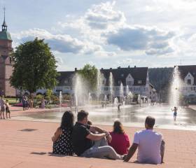 Marktplatz mit bunten Blättern an den Bäumen und Parkbesucher