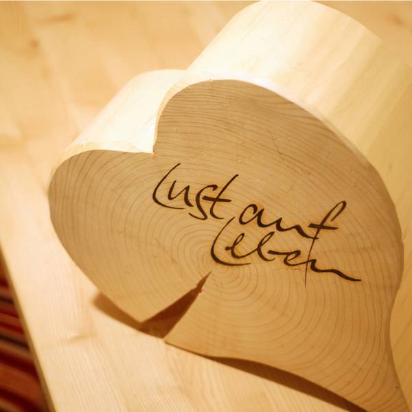 Holzherz mit Schriftzug "Lust auf Leben" auf Holztisch